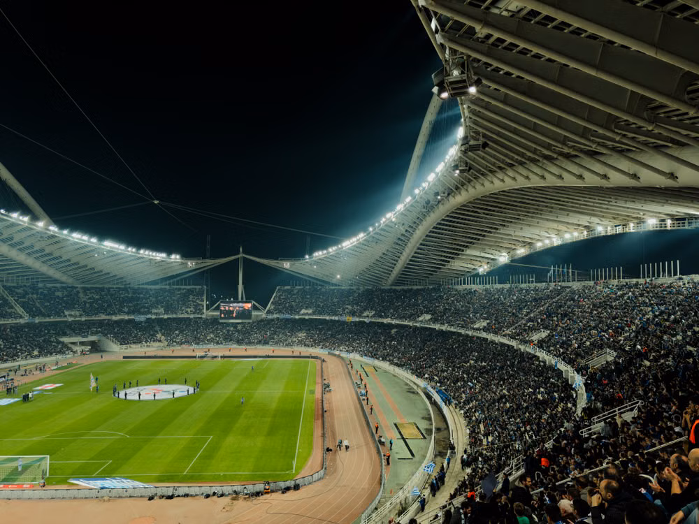Sweeping roof structure above a crowded football stadium at night